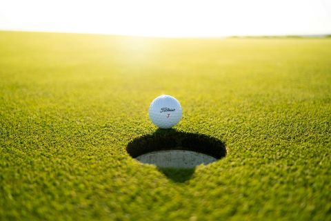 Golf ball sitting on the edge of a golf hole